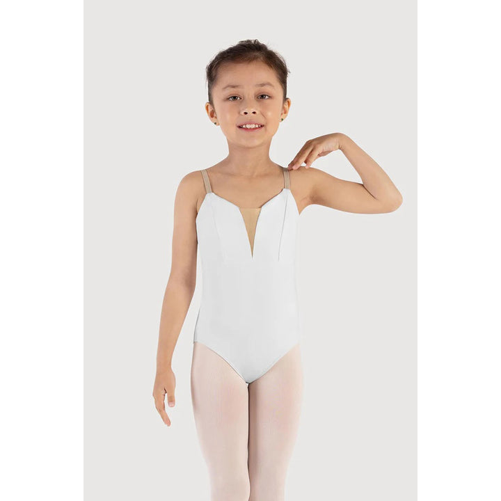 A young girl modeling a white ballet leotard with thin shoulder straps and a V-neckline, paired with light pink tights, against a light gray studio background.