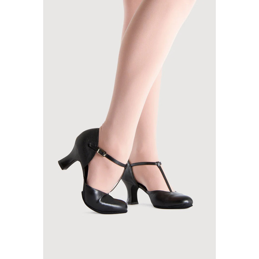 A pair of black leather T-strap high heels with a block heel, shown on a model&